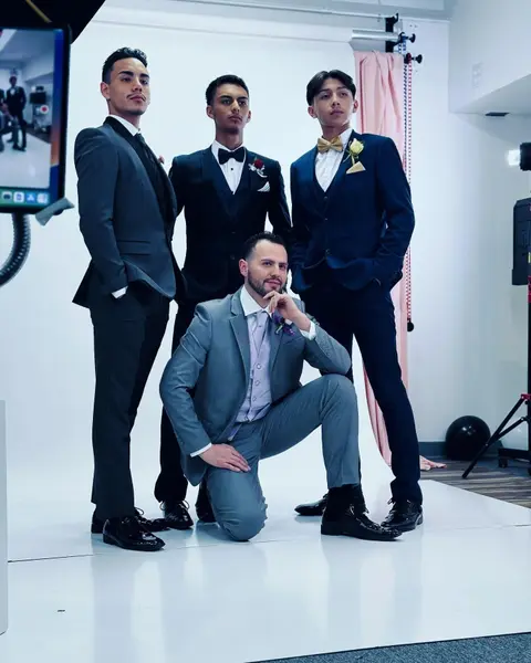 Four groomsmen in charcoal, black, navy and light grey suits in the Royal Tuxedos studio